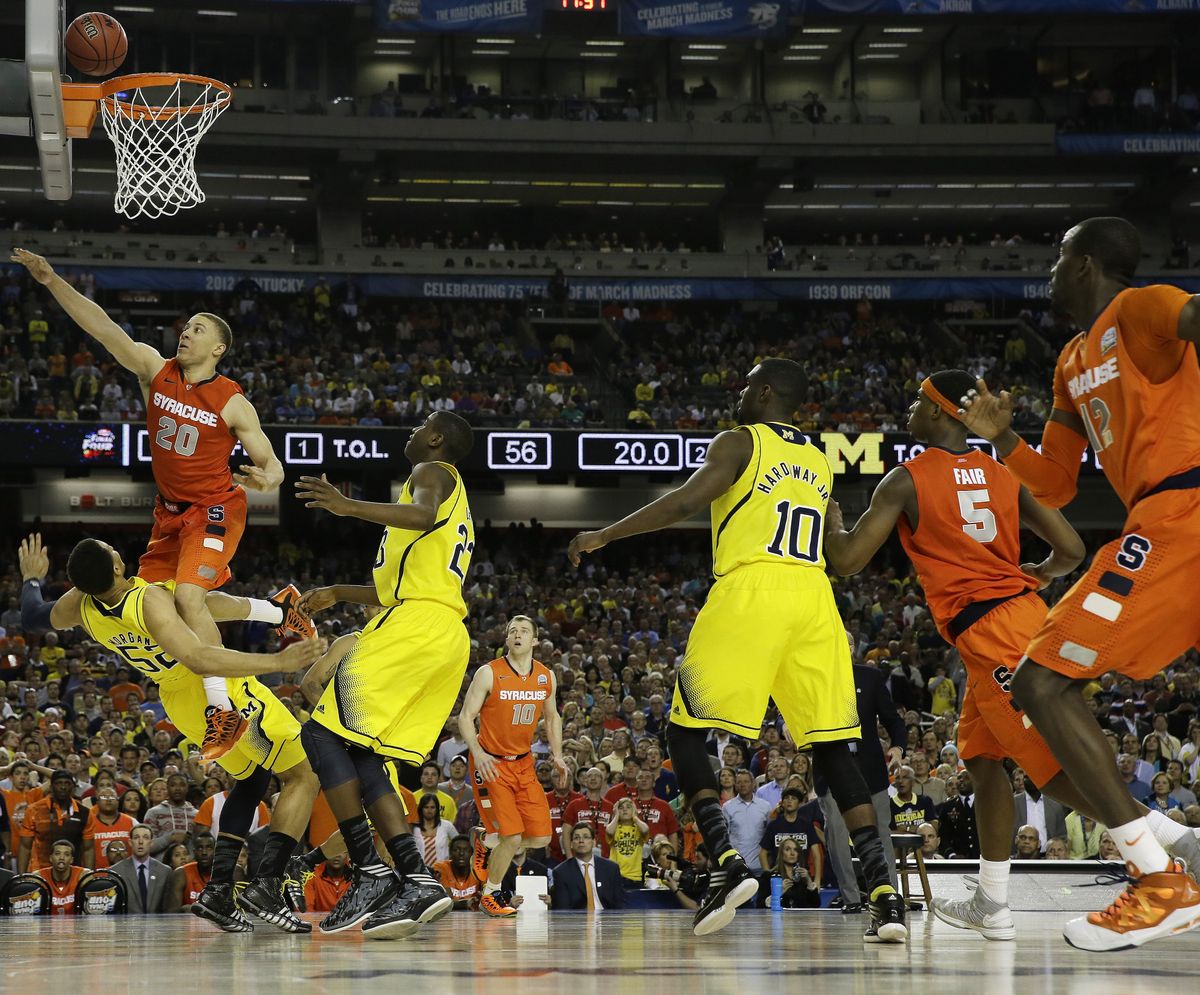 Michigan’s Jordan Morgan takes a charge with 19.2 seconds left on a drive by Brandon Triche of Syracuse, which was trailing by two at the time. (Associated Press)