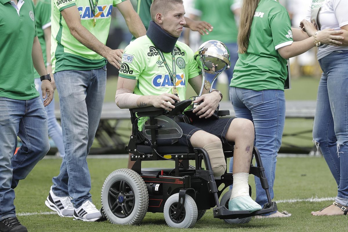 Chapecoense goalkeeper Follmann, one of the three players that survived the air crash almost two months ago, is wheeled on the pitch as he carries the Sudamericana trophy, during the Sudamericana trophy award ceremony prior to a match against Palmeiras, in Chapeco, Brazil, Saturday, Jan. 21, 2017. Almost two months after the air tragedy that killed 71 people, including 19 team players, Chapecoense plays at its Arena Conda stadium against the 2016 Brazilian champion Palmeiras. (Andre Penner / Associated Press)