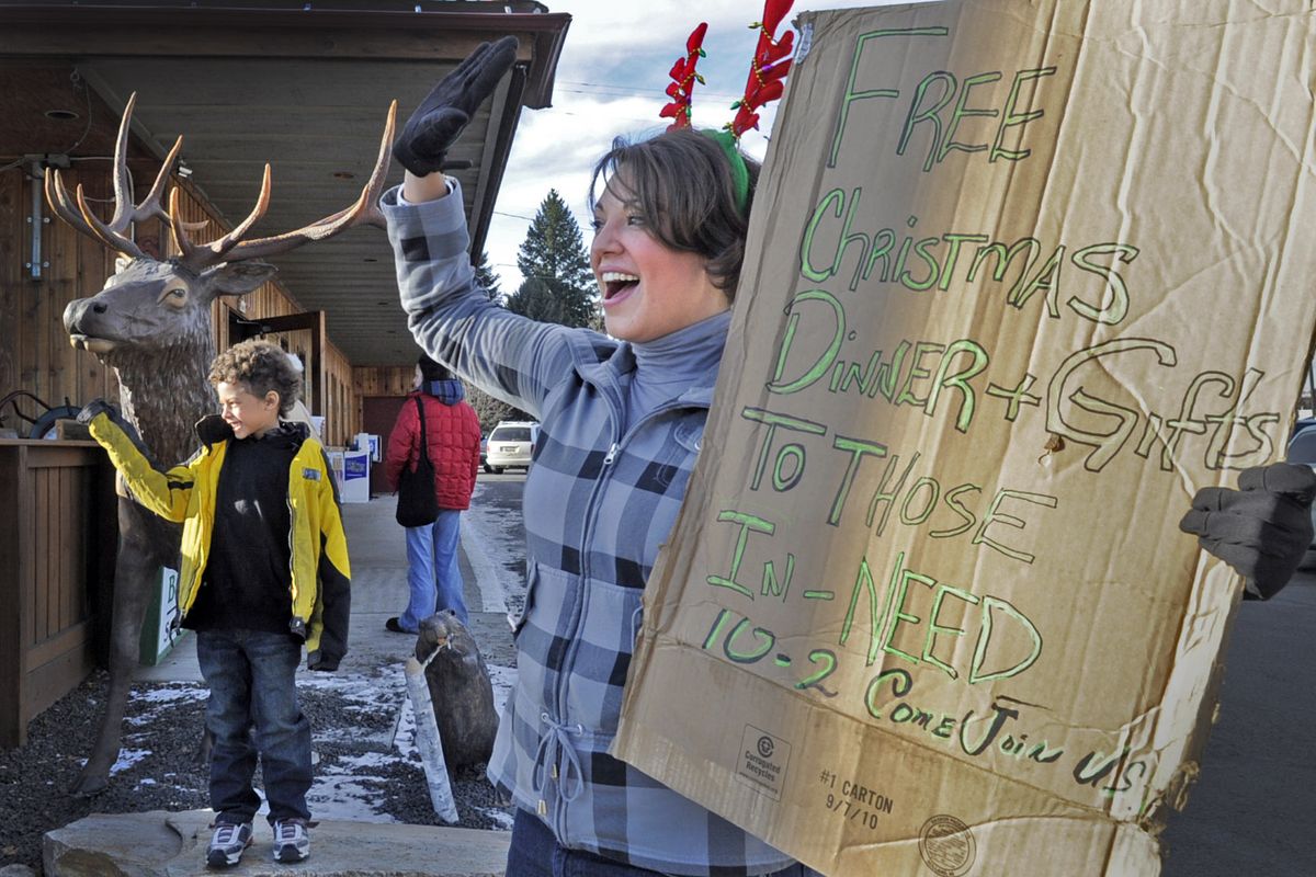 Grace Stamsos wears her antlers and Malcolm Rolling waves to people Saturday as they try to attract people to GW Hunters  in Post Falls for a free Christmas Day dinner. Owner Dave Swanson plans to give away free meals next Thanksgiving and Christmas, too.  (PHOTOS BY CHRISTOPHER ANDERSON)