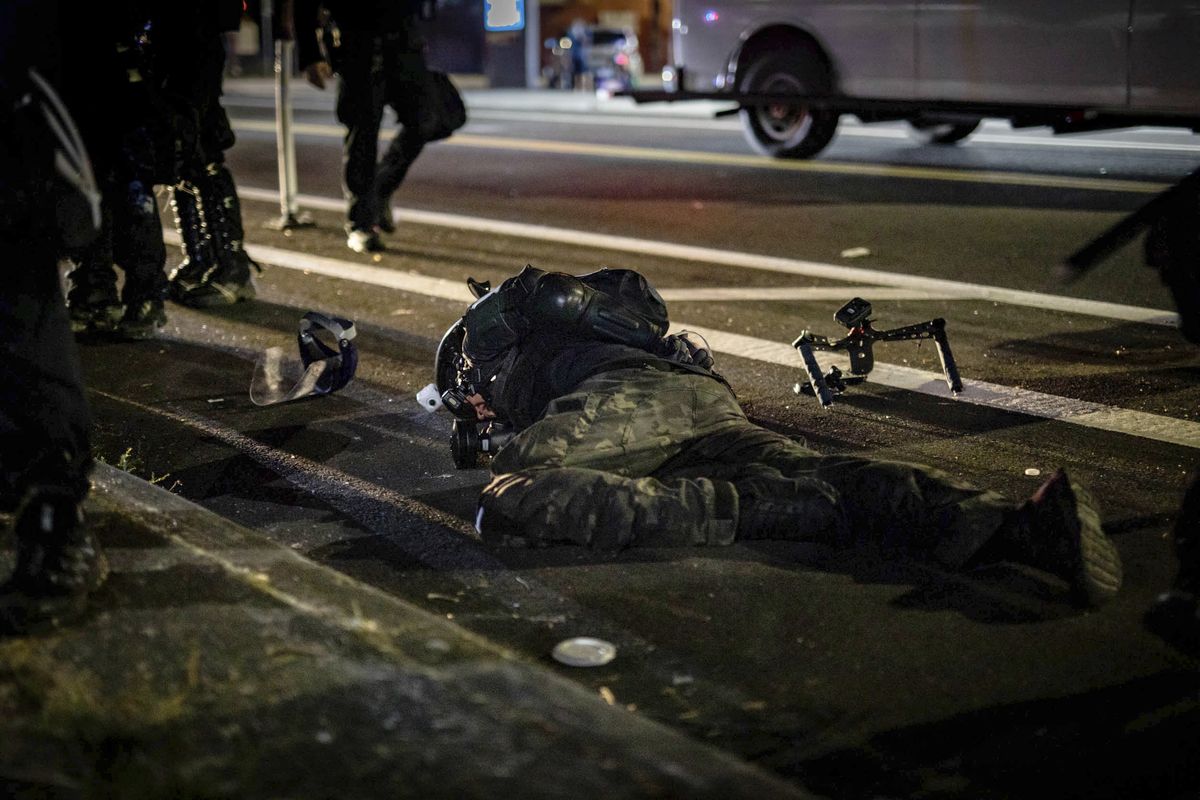 In this Aug. 5, 2020 photo, an activist who was filming protests lies on the street after being tackled by a police officer in Portland, Ore. His camera rig is seen on the ground nearby. Most police officers who violate citizens’ rights get away with it because the law is heavily stacked in their favor, legal experts say.  (Maranie Rae Staab)