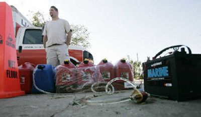 
Evan Einzig uses a battery to power a small pump to fill gas cans for his home's generator in a file photo from Oct. 25, 2005 in Sunrise, Fla. Einzig's family's gas station had gas but no electricity to power the gas pumps. 
 (Associated Press / The Spokesman-Review)