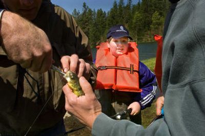
Zach Beach  watches as Chris Cornelius, left, and Paul Hatten pull the hook out of his fish Friday. Spokane Valley firefighters took 40 special needs students from the Central Valley School District fishing at Bear Lake. 
 (CHRISTOPHER ANDERSON / The Spokesman-Review)