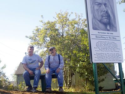 Denny Jackson, left, and Tori Kovach sit on a bench near a new sign on the banks of the Wishkah River in Aberdeen, Wash., Monday.  The duo are building a park there in memory of Kurt Cobain.  (Associated Press / The Spokesman-Review)