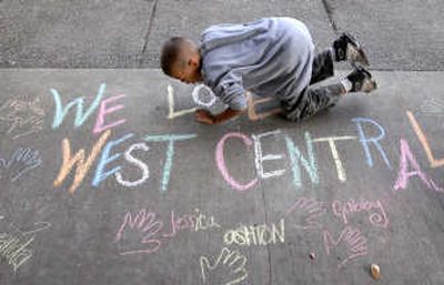 
Isaiah Rivers,  9, blows the chalk dust away from sidewalk artwork he helped create at the A.M. Cannon Park shelter this month. 
 (Dan Pelle / The Spokesman-Review)