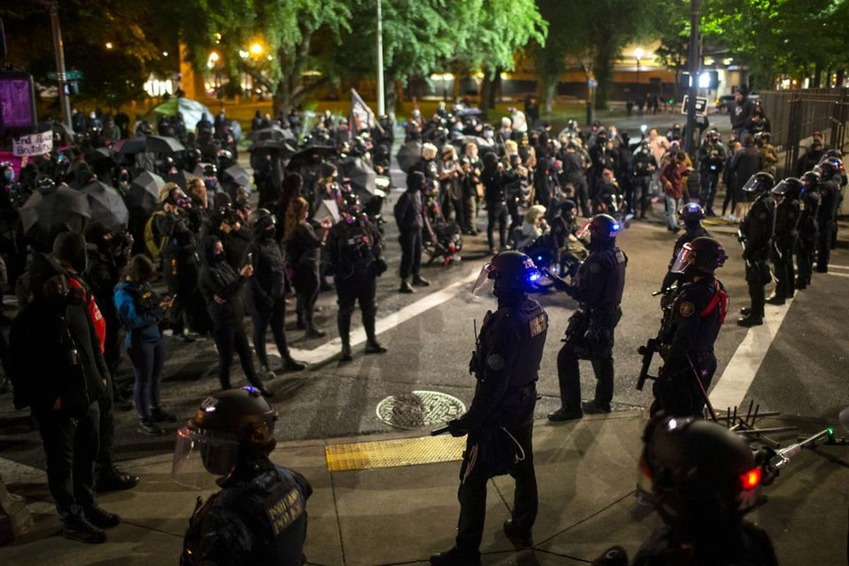 Police and protesters face off Tuesday night after a dumpster was set on fire next to the Justice Center. A group of protesters gathered in downtown Portland on May 25, 2021, to mark the passing of a year since a Minneapolis police officer murdered George Floyd. Later, members of the group marched through the downtown streets, where some broke windows and painted graffiti on buildings. Dave Killen/Staff  (Dave Killen)