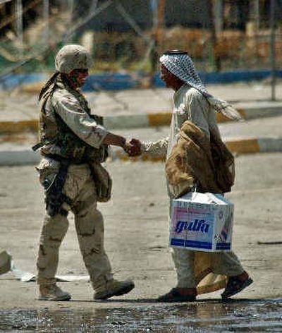 
An American soldier shakes hands with an Iraqi civilian Friday after a peace deal for the three-week standoff was brokered in the southern Iraqi city of Najaf. Guns were quiet in Najaf on Friday for the first time in weeks, after Iraq's top Shiite cleric made a dramatic return to the city.
 (Associated Press / The Spokesman-Review)