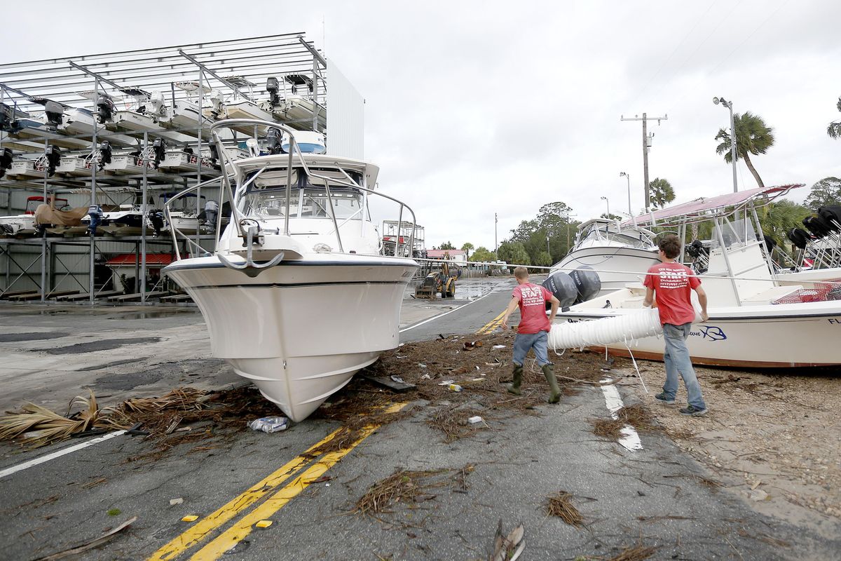 People walk pass debris and boats scattered across the road after Hurricane Hermine passed the area on Friday, Sept. 2, 2016 in Steinhatchee, Fla. Hermine was downgraded to a tropical storm after it made landfall, as it moves over Georgia, but the U.S. National Hurricane Center says winds are increasing along the Southeast coast and flooding rains continue. (Matt Stamey / The Gainesville Sun via AP)