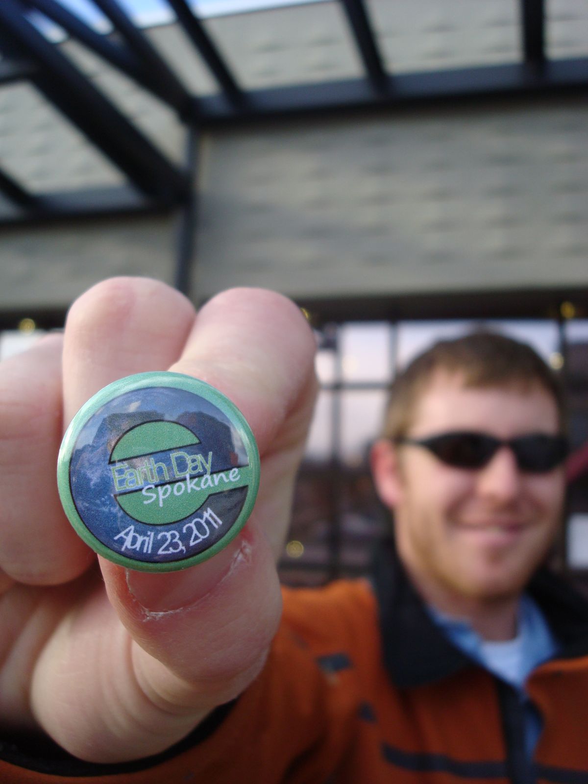 Bart Mihailovich, Spokane Riverkeeper and co-chair for Earth Day Spokane,  2011, shows one of the buttons created to promote the April 23 event. This year it will return to Main and Browne for a day-long celebration with music, vendors, food and more.   (Shallan Knowles / Down to Earth NW Correspondent)