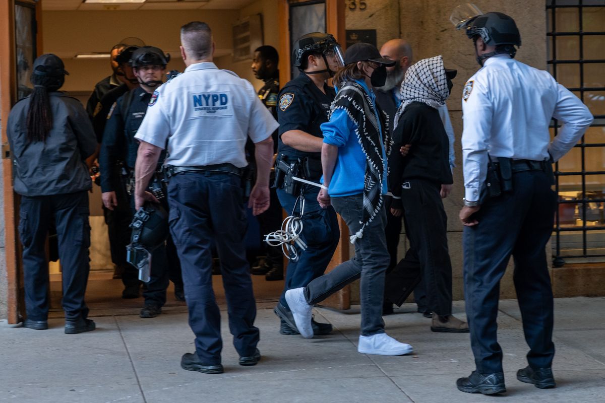 Pro-Palestinian protesters are escorted out of Columbia University’s Butler Library on Wednesday after their arrest for occupying the library space in New York City. Crowds of protesters grew as a standoff with security at the library continued into the evening. (Spencer Platt)