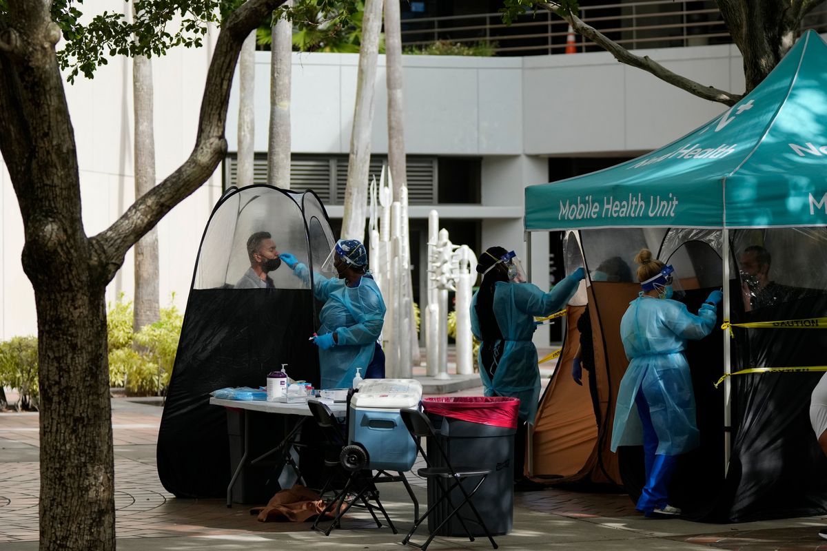 FILE - People are tested for COVID-19, at a walk-up testing site run by Nomi Health, Tuesday, Dec. 28, 2021, in downtown Miami. More than a year after the vaccine was rolled out, new cases of COVID-19 in the U.S. have soared to the highest level on record at over 265,000 per day on average, a surge driven largely by the highly contagious omicron variant. (Rebecca Blackwell)