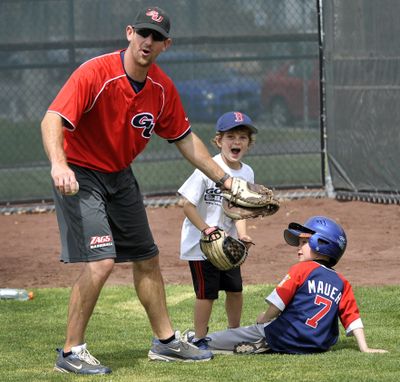 Waiting for the call: Coach Brian Munhall and player, Max Williams, 7, wait for a ruling on a sliding Logan Nagle, 6, during the Zags Baseball Camp on the Gonzaga University campus. The three-day camp features fundamentals in the morning and games in the afternoon. Nagle was called out on the play. (Dan Pelle)