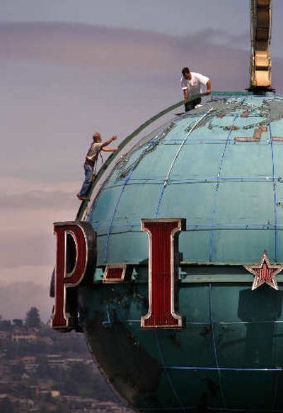 
A pair of workers stand atop the landmark globe on the roof of the building housing the Seattle Post-Intelligencer during maintenance work on Thursday. 
 (Associated Press / The Spokesman-Review)