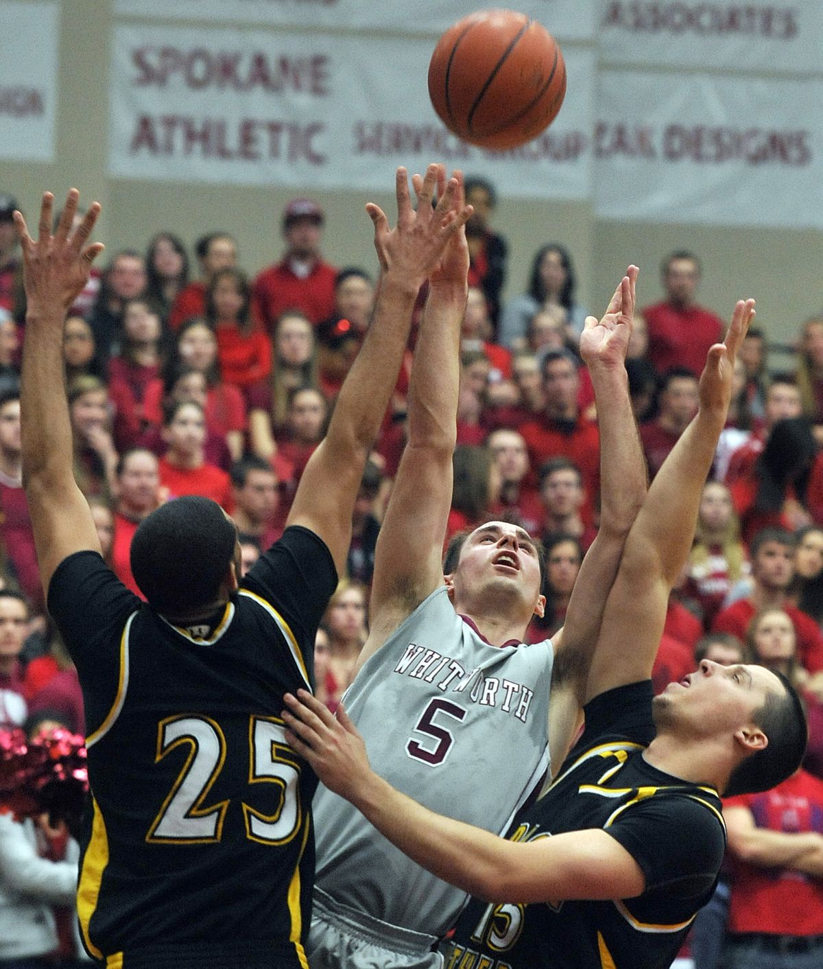 Whitworth’s Mike Taylor (5) slices through PLU’s defense of Victor Bull (25) and Kai Hoyt for a shot. (Dan Pelle)