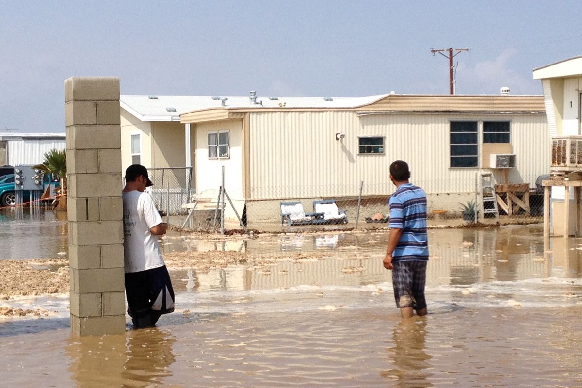Two men stand in near knee deep water in a mobile home park in Mecca, Calif.  after a sudden heavy rain flooded the area early , Tuesday, Sept. 11, 2012.  Early morning thunderstorms over southeastern California