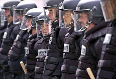 Riot police line up outside FleetCenter as anti-war and anti-Bush protesters shout through a fence in Boston on Sunday.
(Associated Press / The Spokesman-Review)