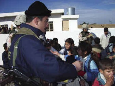 
A local police officer hands out cookies to schoolchildren at the Allo Mahmoud Health Clinic opening ceremony on Dec. 21. 
 (Photo courtesy of Lt. Col. Gordon Petrie / The Spokesman-Review)