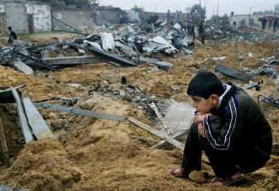 
A Palestinian boy crouches amid the destruction as others search through the rubble of destroyed houses after an Israeli army raid in the Khan Younis refugee camp, southern Gaza Strip, on Sunday. 
 (Associated Press / The Spokesman-Review)