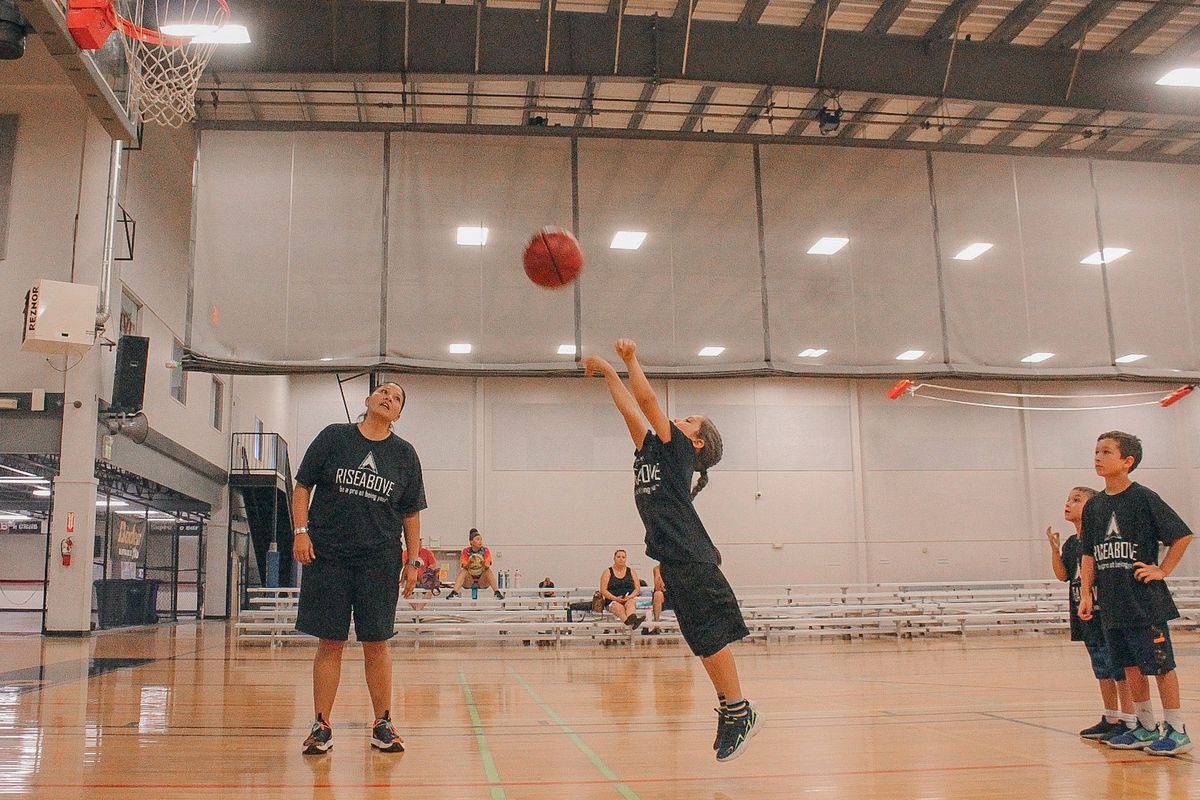 Jaci McCormack, left, watches as kids shoot baskets at the Rise Above basetball camp, which she organizes, Monday, July 12, 2021 at the Hub Sports Center in Liberty Lake. The program focuses on Native youth and is free for them to attend. (Jordan Tolley-Turner/THE SPOKESMAN-REVIEW)