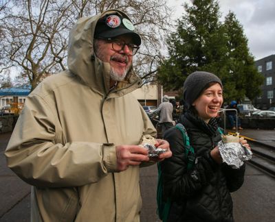 Ken Neubeck, left, and Tessa Barker take a break Dec. 20 from volunteering with the Occupy Medical Group to enjoy a burrito from the Burrito Brigade in Eugene, Ore.