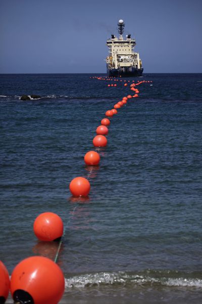A fiber-optic cable, suspended from buoys, is rolled out by a ship off the Venezuelan coast Saturday.  (Associated Press)