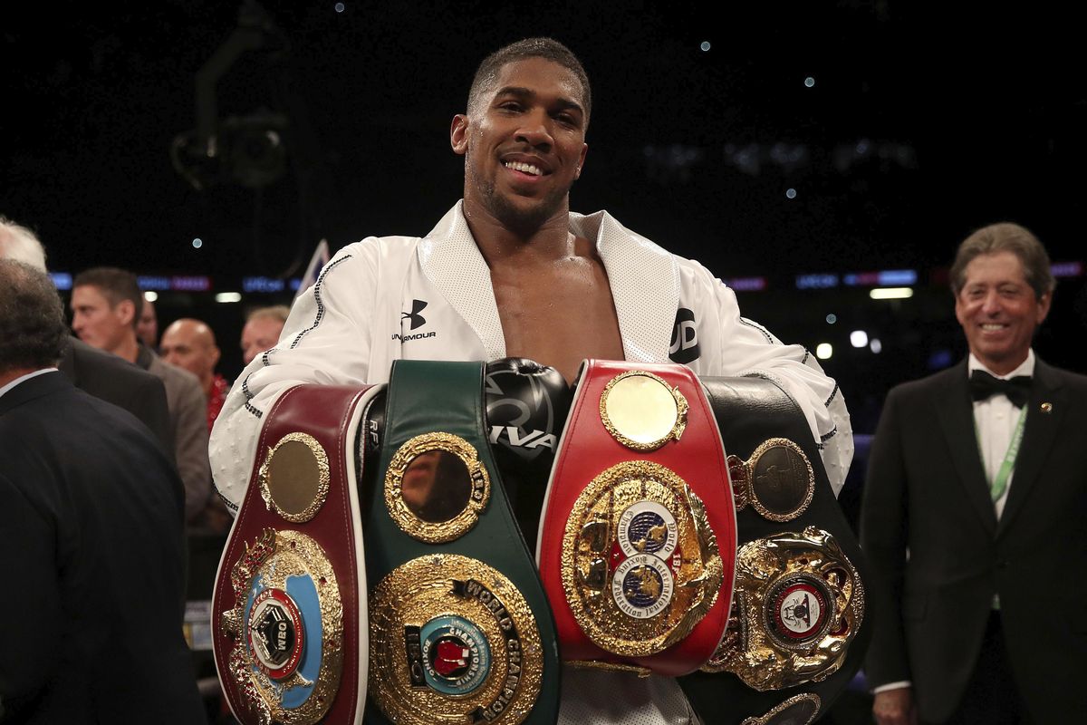 Anthony Joshua celebrates with his belts after victory over Joseph Parker to become the WBA, IBF and WBO heavyweight champion at the Principality Stadium in Cardiff, Wales, Saturday March 31, 2018. (Nick Potts / Associated Press)