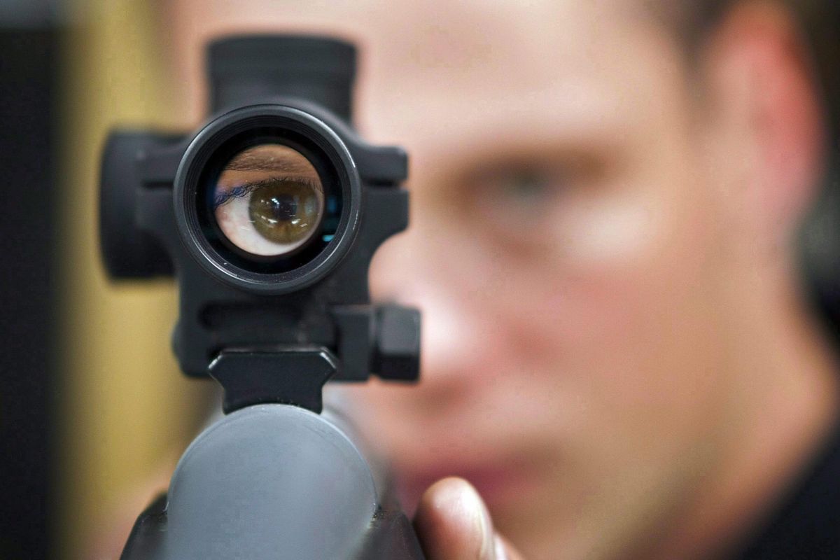 An employee looks through the scope of long gun at a gun store in Calgary, Alberta, Canada, on Sept. 15, 2010. When Canada first sought to restrict gun access in the 1990s, the National Rifle Association threatened a boycott by U.S. hunters spending tourism dollars in the country. (Jeff McIntosh/The Canadian Press via Associated Press)