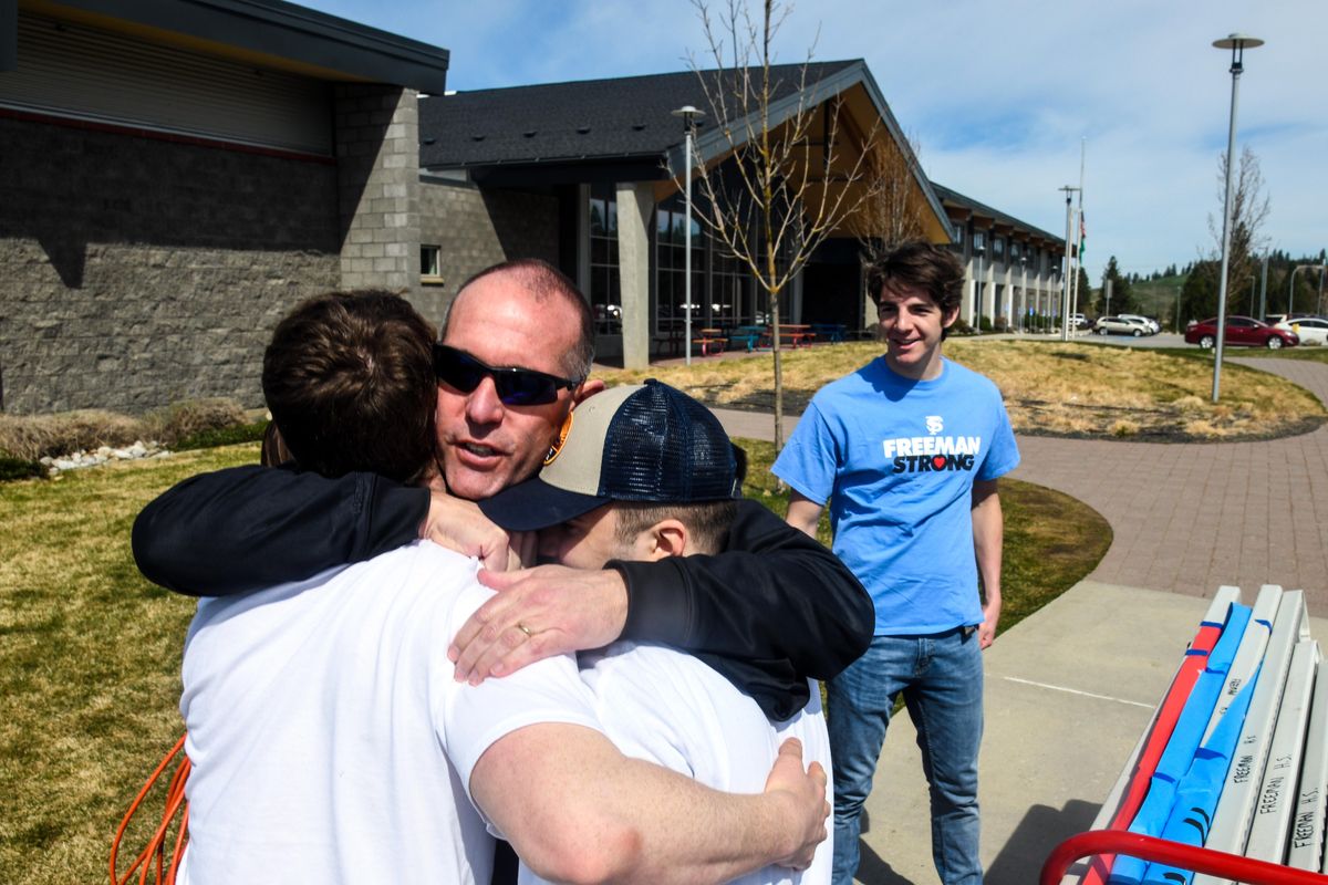 Freeman School District Superintendent Randy Russell embraces Konner Freudenthal. left, and Dylan Pavlischak, as Jackson Clark looks on, after students marched from the school to the football field to participate in a nation-wide walkout to protest gun violence, Friday, April 20, 2018. (Dan Pelle / The Spokesman-Review)