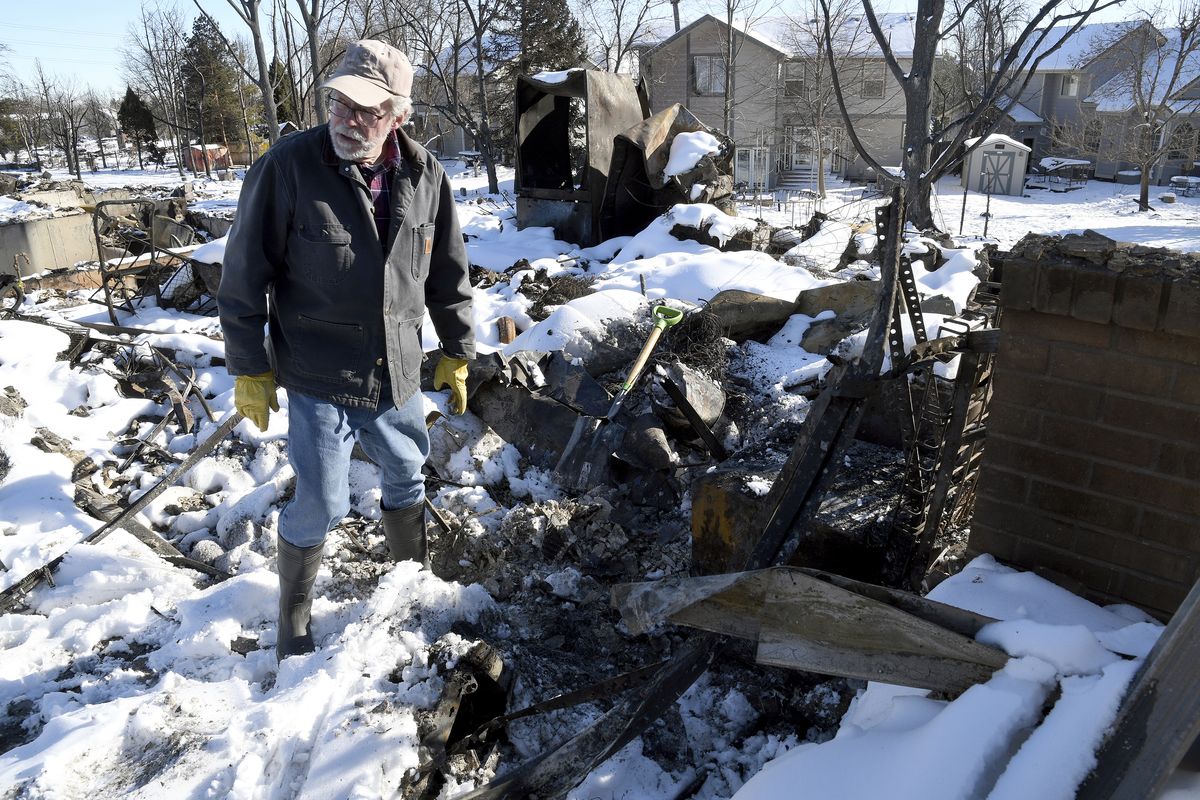 FILE - Rex Hickman sifts through the rubble of his burned home in Louisville, Colo., Sunday, Jan. 2, 2022. Some homeowners recovering from Colorado
