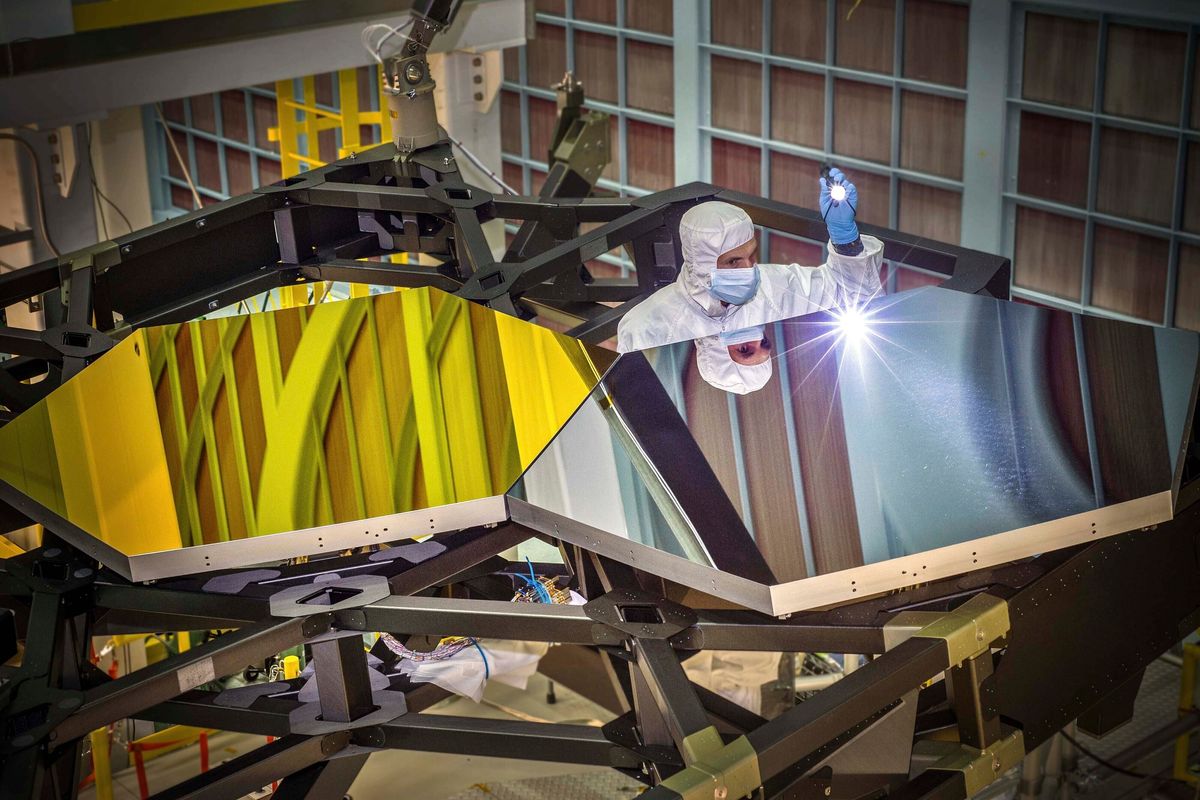 In this Sept. 29, 2014 photo made available by NASA, James Webb Space Telescope Optical Engineer Larkin Carey examines two test mirror segments on a prototype at the Goddard Space Flight Center