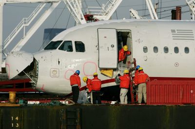 A man hands items out of US Airways Flight 1549 as other inspectors examine items from inside the plane as it sits on a barge at Weeks Marina on Tuesday in Jersey City, N.J.  (Associated Press / The Spokesman-Review)