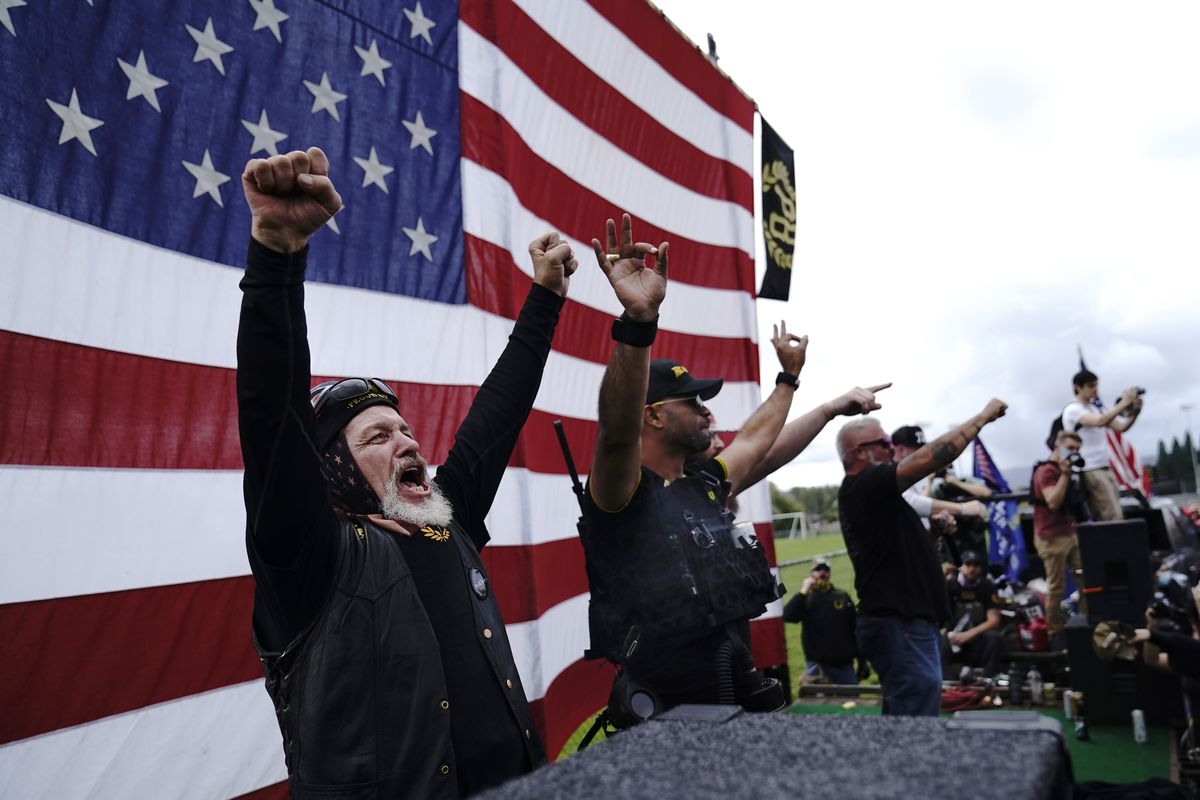 FILE - In this Sept. 26, 2020 file photo, members of the Proud Boys, including leader Enrique Tarrio, second from left, gesture and cheer on stage as they and other right-wing demonstrators rally in Portland, Ore. President Donald Trump didn