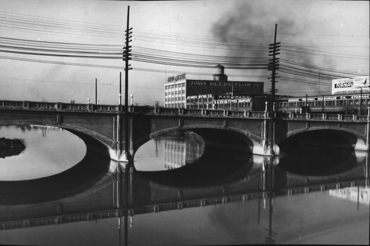 1935: Seen beyond the Division Street Bridge, several warehouses, including the five-story John Deere Plow Company building, were built along the Spokane International Railway’s tracks between Washington and Division streets in the early 20th century. The connection of the Spokane International put the Canadian Pacific line into serious competition in the Lower 48. Passenger traffic tapered off through the 20th century, and the Spokane International depot and most tracks were removed for Expo ’74.  (Spokesman-Review Photo Archives)