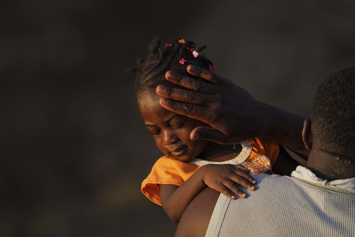 A man carries a girl across the Rio Grande river as migrants, many from Haiti, leave Del Rio, Texas to return to Ciudad Acuna, Mexico, early Wednesday, Sept. 22, 2021, some to avoid possible deportation from the U.S. and others to get supplies.  (Fernando Llano)