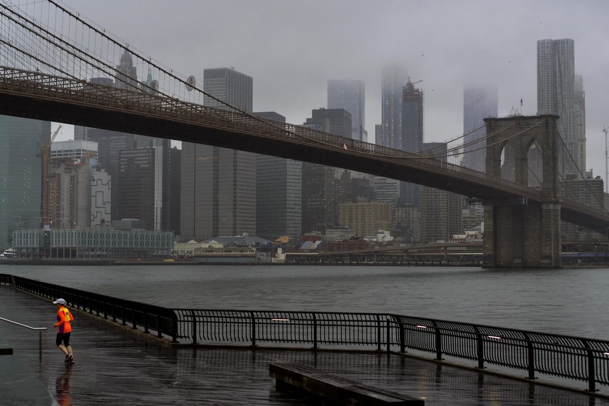 A runner moves along the Brooklyn shoreline of the East River as rain and clouds loom over lower Manhattan on the fifth anniversary of Superstorm Sandy Sunday, Oct. 29, 2017, in New York. (Craig Ruttle / Associated Press)