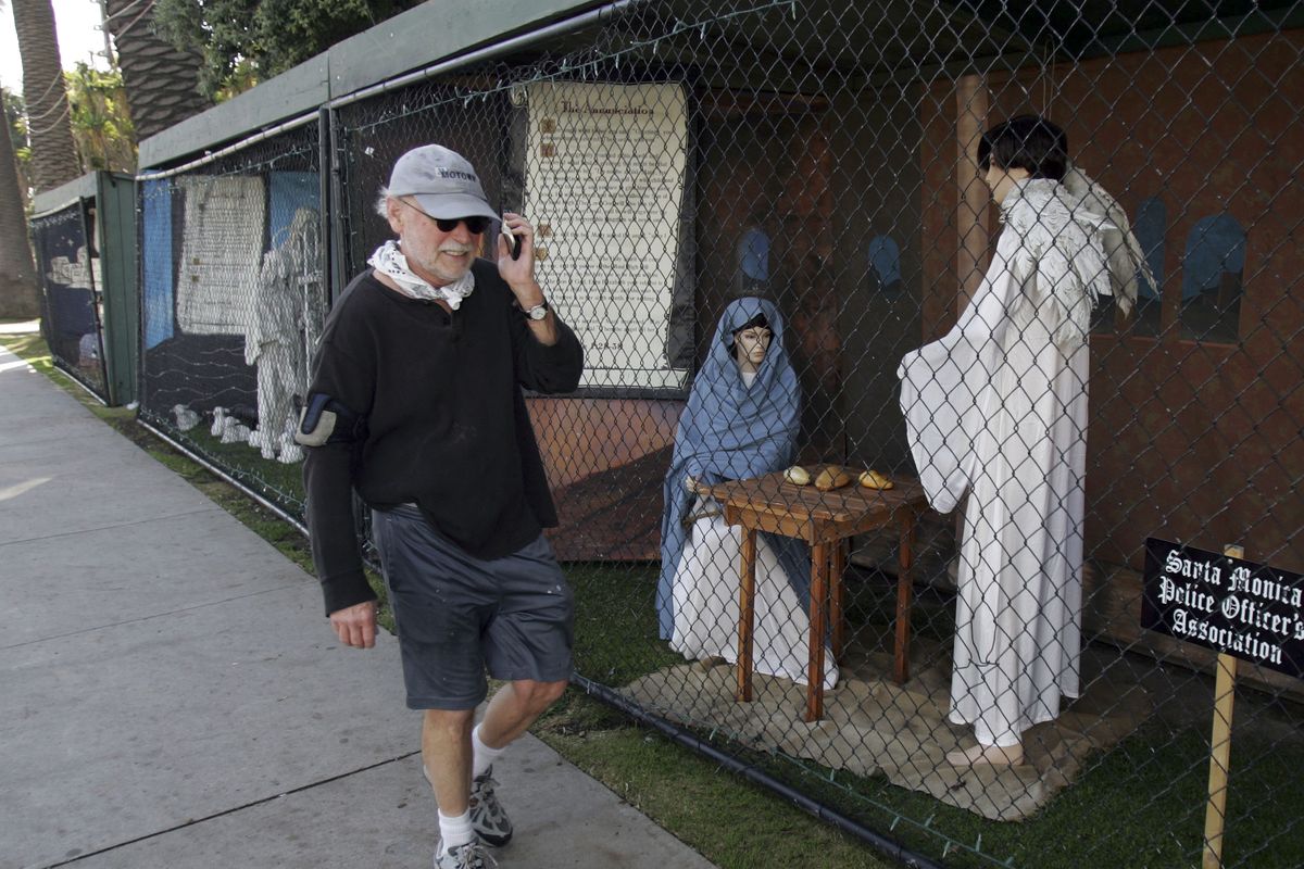 FILE - In this Dec. 13, 2011 file photo, a man walks past two of the traditional Nativity scenes along Ocean Avenue at Palisades Park in Santa Monica, Calif. Avowed atheist Damon Vix last year won two-thirds of the booths in the annual, city-sponsored lottery to divvy up spaces in the live-sized Nativity display.  But he only put up one thing: A sign that read "Religions are all alike - founded on fables and mythologies." Vix left the rest of his allotted spaces empty, and in so doing, upended a Christmas tradition that began in Santa Monica nearly 60 years ago. (Ringo Chiu / Fr170512 Ap)