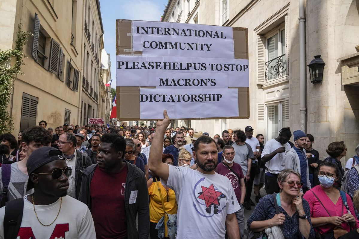 An anti-vaccine protester holds a placard Saturday during a rally in Paris. Tens of thousands of people took to the streets against the government.  (Michel Euler)