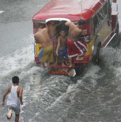 
A boy tries to catch up to a passenger vehicle plowing through floodwaters Sunday in Manila. Associated Press
 (Associated Press / The Spokesman-Review)