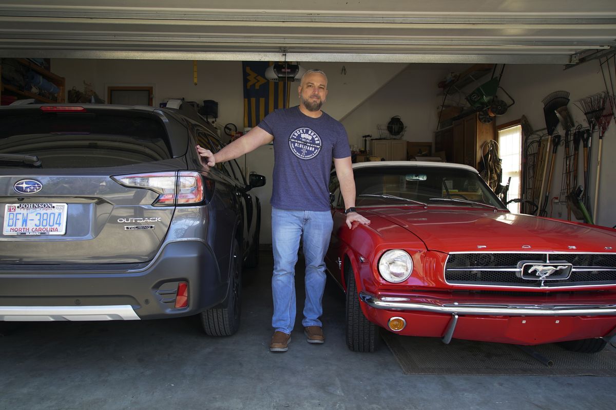 Steve Bock stands between his new Subaru Outback and his 1965 Ford Mustang at his home in Apex, N.C., on March 5. Bock would like to have an electric car, but says the prices will have to come down.  (Associated Press)
