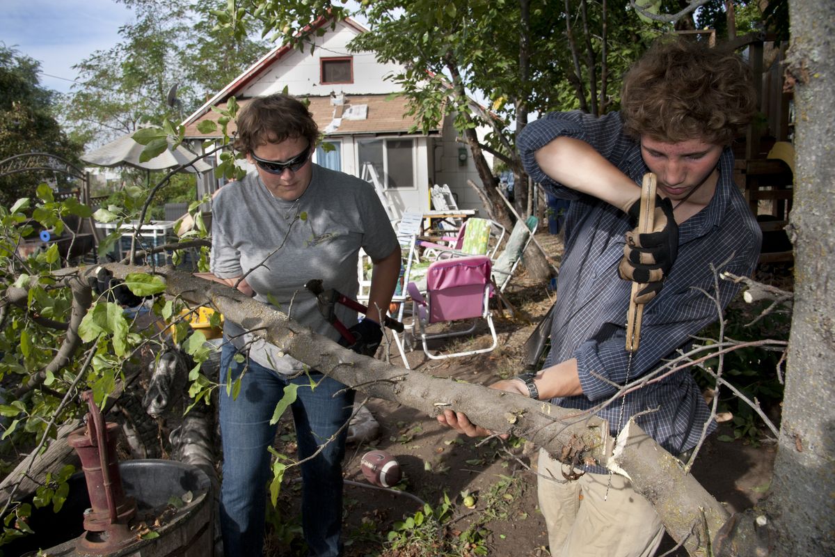 Jenn Guhl and Isaac Brown trim an apple tree branch in Gary Rohan’s backyard Saturday in northeast Spokane. Hundreds of volunteers cleaned up streets and yards and performed small maintenance projects in the Logan neighborhood. (Dan Pelle)