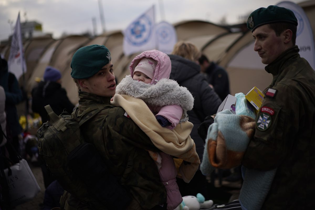 A Polish soldier holds a baby as refugees fleeing war in neighboring Ukraine arrive at the Medyka crossing border, Poland, Thursday, March 10, 2022.  (Daniel Cole)