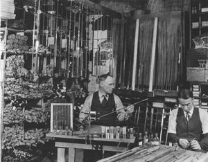 1925. John T. Little's Sporting Goods shop on N. Howard between Main and Riverside. Little, left, and Eugene Parsons, right, are shown working on bamboo fishing poles. 