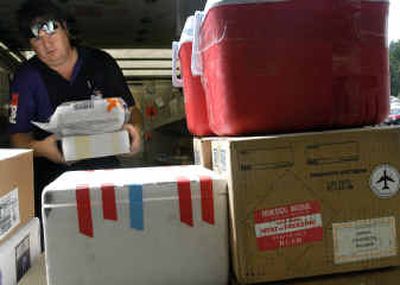 
Federal Express driver Brian Paynter unloads a cart full of boxes, including four containing BSE testing samples for the disease diagnostic laboratory at Washington State University.
 (Kevin Nibur/ / The Spokesman-Review)
