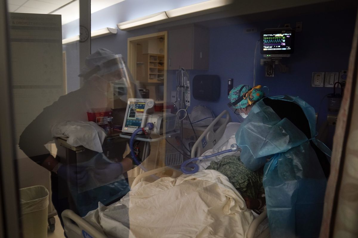 Registered nurses Kyanna Barboza, right, tends to a COVID-19 patient as Kobie Walsh puts on her PPE at St. Joseph Hospital in Orange, Calif. Thursday, Jan. 7, 2021. California health authorities reported Thursday a record two-day total of 1,042 coronavirus deaths as many hospitals strain under unprecedented caseloads. The state