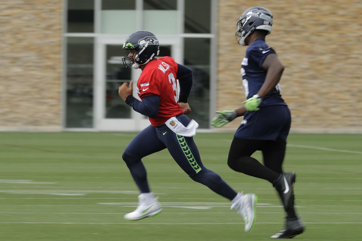 Seattle Seahawks quarterback Russell Wilson, left, runs with tight end Tyrone Swoopes, right, during NFL football practice, Thursday, June 14, 2018, in Renton, Wash. (Ted S. Warren / Associated Press)