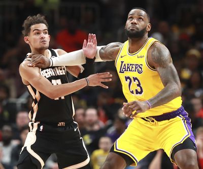 Los Angeles forward LeBron James, right, pushes Atlanta guard Trae Young as he prepares to grab a jump ball Sunday in Atlanta. (Curtis Compton / Associated Press)