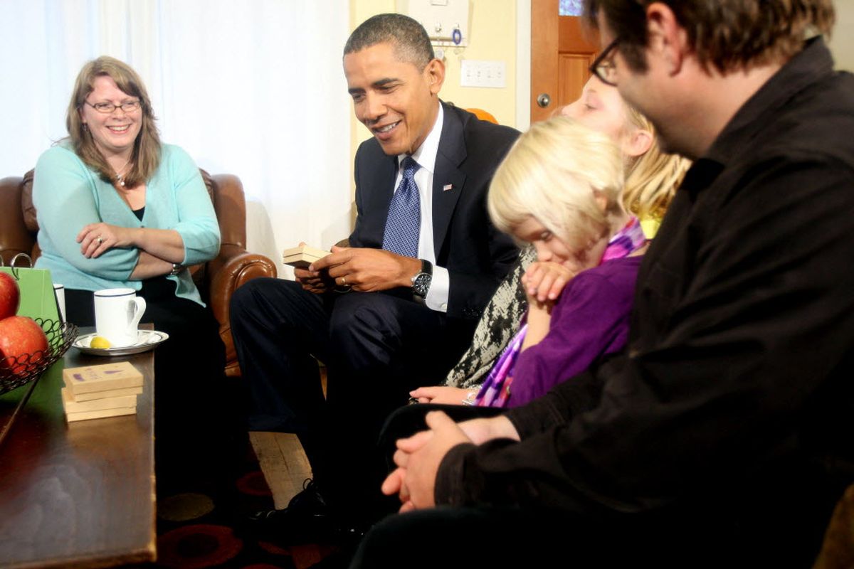 President Barack Obama talks with Erik Foss, his wife Cynnie, left, and their daughters Anna, 8, and Elsa, 5, in the living room of their home in Seattle today. (Mike Siegel / Associated Press)