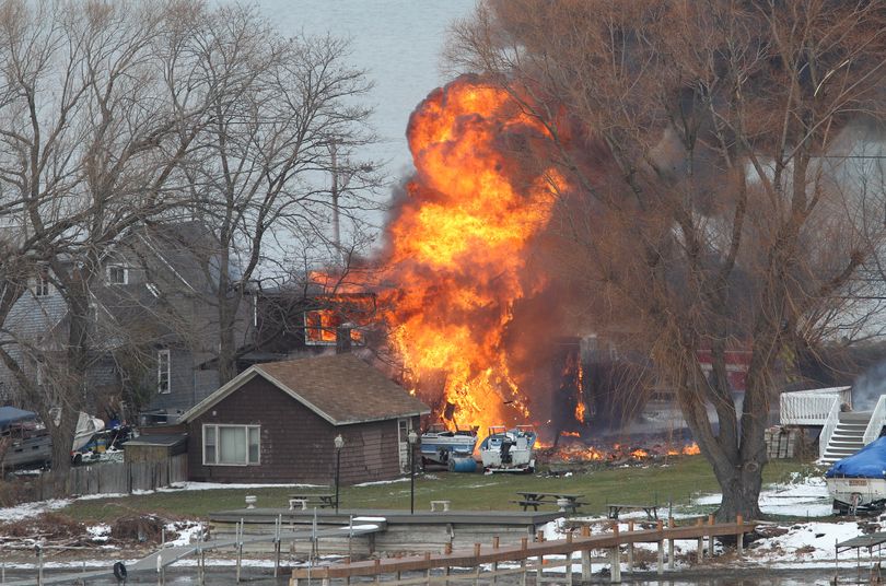 A house burns Monday in Webster, N.Y. A former convict set a house and car ablaze in his lakeside New York state neighborhood to lure firefighters then opened fire on them, killing two and engaging police in a shootout before killing himself. (Associated Press)