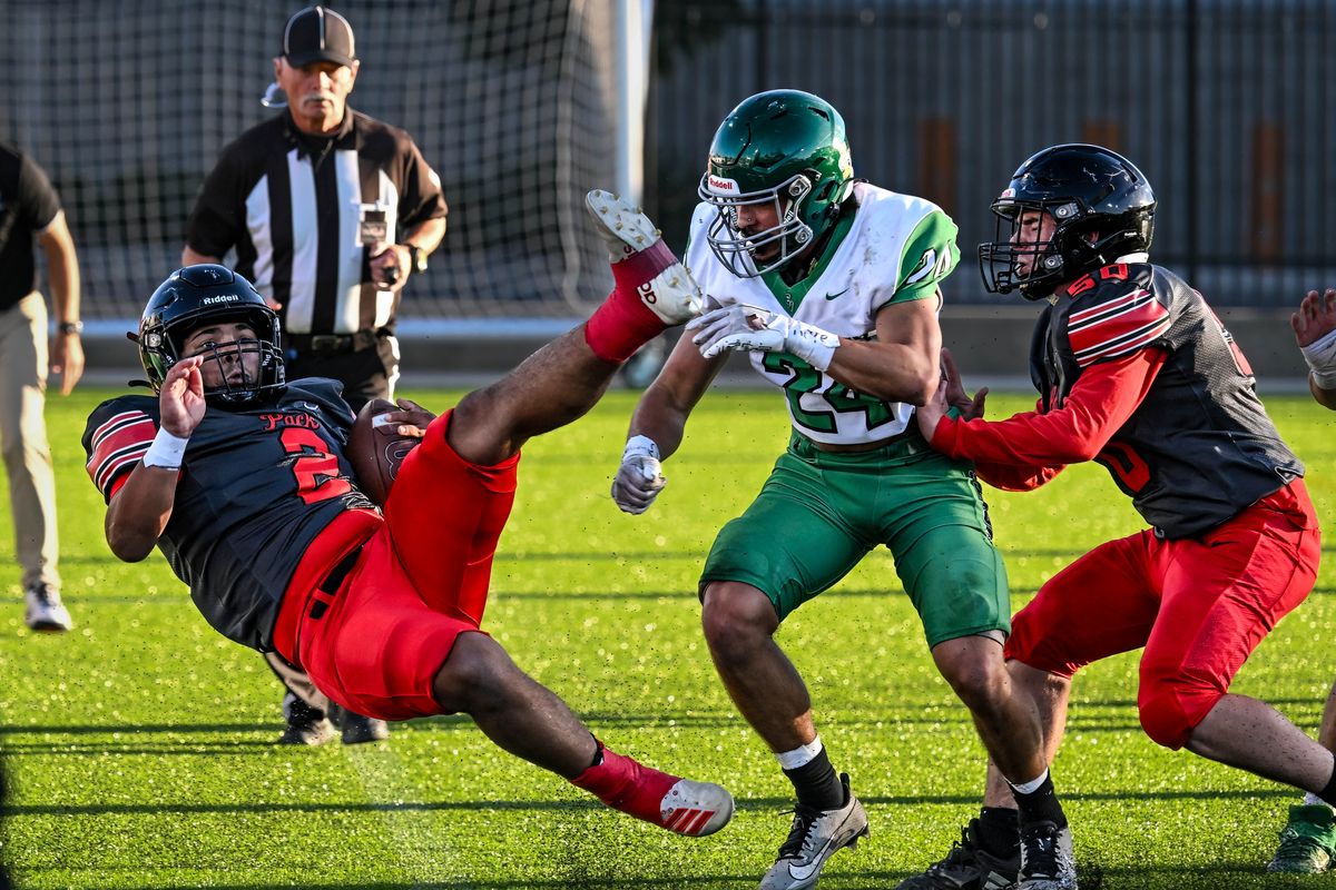 North Central running back Trey Workman (2) gets a first down, but takes a hard hit on the sideline by East Valley safety Diesel Wilkinson (24) during the first half of a GSL 2A high school football game, Thursday Oct. 5, 2023, in One Spokane Stadium.  (Colin Mulvany/The Spokesman-Review)