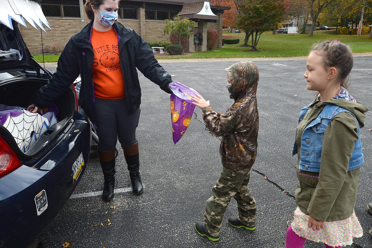 Samantha Ruiz-Bueno, left, passes out candy to Boaz Pettis, 6, of Millcreek Township, Pa., and his sister Callista Pettis, 8, during the Drive-thru Trunk or Treat event for kids Saturday at the Fairview United Methodist Church in Fairview, Pa.  (Jack Hanrahan)