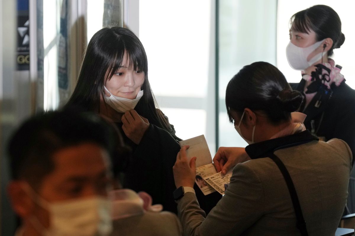 Japan’s former Princess Mako, left, the elder daughter of Crown Prince Akishino, lowers her mask to board a plane bound for New York with her husband, Kei Komuro, on Sunday at Tokyo International Airport.  (Eugene Hoshiko)